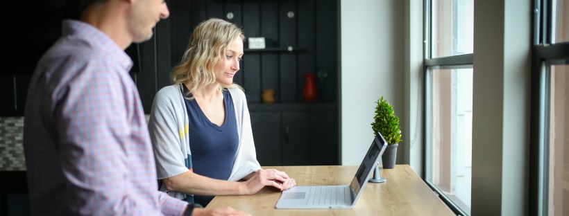 Two employees standing at a desk working on a laptop